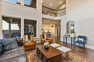 Living room with engineered hardwood flooring, an inviting chandelier, and a towering ceiling