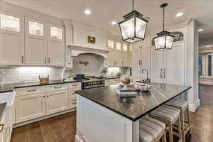 Kitchen with engineered hardwood flooring, an island with sink, tasteful backsplash, and pendant lighting