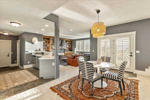 Tiled dining space featuring built in features, sink, and a textured ceiling