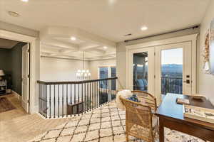 Carpeted office space with an inviting chandelier, coffered ceiling, beam ceiling, and a mountain view