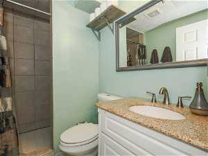 Bathroom with curtained shower, toilet, and vanity with extensive cabinet space