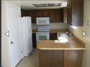 Kitchen with white appliances, kitchen peninsula, dark brown cabinets, and sink