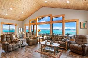 Living room with a water view, dark LVP  floors, wood ceiling, and a wealth of natural light