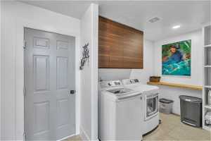 Washroom featuring light tile floors, cabinets, and separate washer and dryer