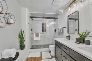 Bathroom featuring toilet, double vanity, hardwood / wood-style floors, a textured ceiling, and walk in shower