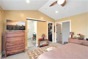 Bedroom with light colored carpet, a spacious closet, ensuite bath, ceiling fan, and lofted ceiling
