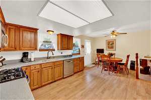 Kitchen with stainless steel dishwasher, light wood-type flooring, tasteful backsplash, ceiling fan, and sink