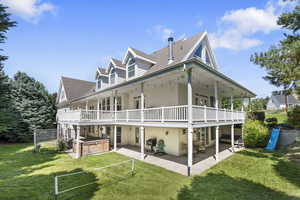 Back of property featuring a patio, a hot tub, and a lawn