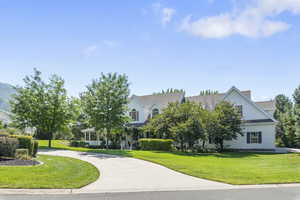 View of property hidden behind natural elements featuring a front yard