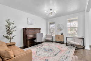 Living area featuring dark hardwood / wood-style floors, a textured ceiling, and a notable chandelier