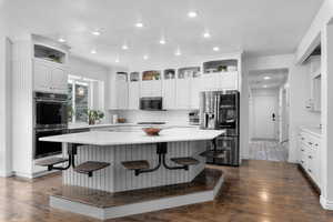 Kitchen with a kitchen island, dark wood-type flooring, appliances with stainless steel finishes, and a breakfast bar