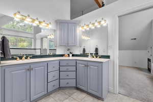 Bathroom featuring dual vanity, tile flooring, and vaulted ceiling