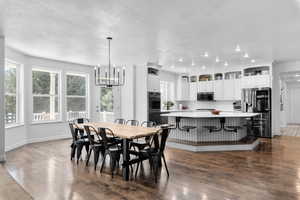 Dining room featuring dark hardwood / wood-style floors, a textured ceiling, a notable chandelier, and a wealth of natural light