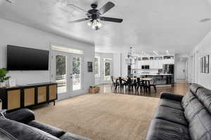 Living room featuring hardwood / wood-style floors, ceiling fan with notable chandelier, and french doors