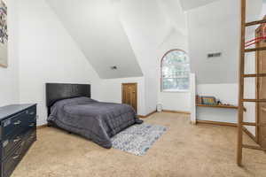 Bedroom with light colored carpet and vaulted ceiling