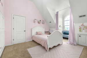 Bedroom with light colored carpet and lofted ceiling