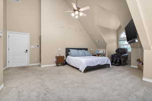 Carpeted bedroom featuring ceiling fan and high vaulted ceiling