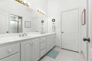 Bathroom with dual sinks, large vanity, and tile floors