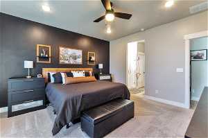 Bedroom featuring ceiling fan, light colored carpet, and ensuite bath