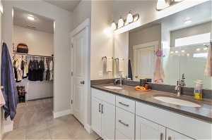 Bathroom with tile flooring, double sink, and vanity with extensive cabinet space
