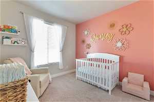 Bedroom featuring light colored carpet and a nursery area