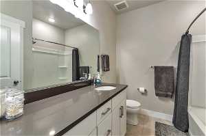 Full bathroom with vanity with extensive cabinet space, toilet, tile floors, and shower / bath combo with shower curtain