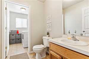 Bathroom featuring washer and dryer, oversized vanity, toilet, and tile floors