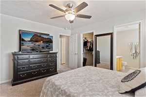 Carpeted bedroom with connected bathroom, a spacious closet, ceiling fan, a textured ceiling, and a closet