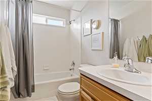 Full bathroom featuring toilet, shower / bathtub combination with curtain, and large vanity