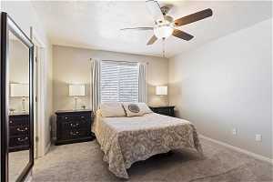 Bedroom with ceiling fan, a textured ceiling, and light colored carpet