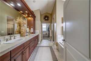 Bathroom featuring plus walk in shower, double sink, vanity with extensive cabinet space, and tile flooring