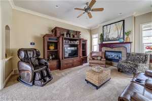 Living room featuring plenty of natural light, ceiling fan, ornamental molding, and light carpet