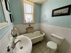 Bathroom with toilet, sink, a tub, a textured ceiling, and tile flooring