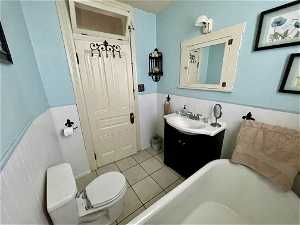 Bathroom featuring toilet, a bathtub, vanity, tile walls, and tile floors