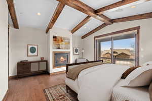 Bedroom featuring dark hardwood / wood-style flooring, lofted ceiling with beams, and access to exterior