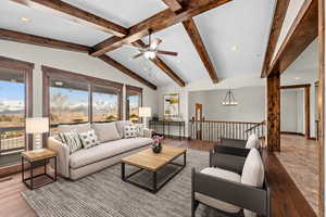 Living room with ceiling fan with notable chandelier, lofted ceiling with beams, and light hardwood / wood-style flooring