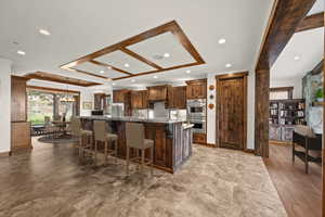 Kitchen featuring stone counters, a kitchen breakfast bar, appliances with stainless steel finishes, a large island, and light hardwood / wood-style floors