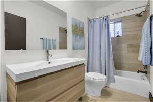 Full bathroom with shower / bath combo with shower curtain, toilet, and vanity