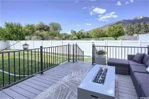 Wooden deck featuring a lawn, an outdoor living space with a fire pit, and a mountain view