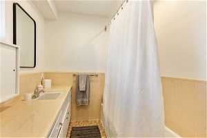 Bathroom with backsplash, tile walls, tile floors, and vanity with extensive cabinet space