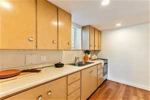 Kitchen with stainless steel gas stove, backsplash, sink, and hardwood / wood-style floors