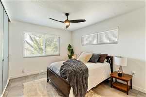 Bedroom featuring ceiling fan, a closet, light tile floors, and a textured ceiling