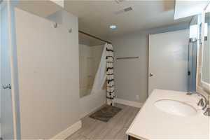 Bathroom with shower / tub combo, vanity, and hardwood / wood-style floors