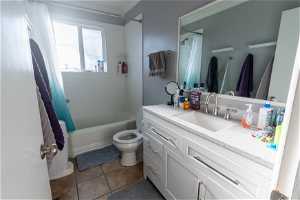 Full bathroom featuring toilet, oversized vanity, shower / tub combo with curtain, and tile flooring