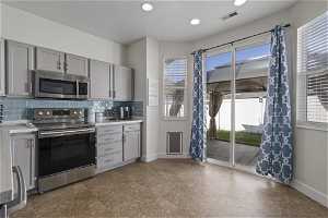 Kitchen with tasteful backsplash, dark tile flooring, stainless steel appliances, and gray cabinetry