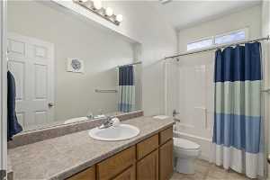 Full bathroom featuring tile flooring, vanity, shower / bath combo, and toilet