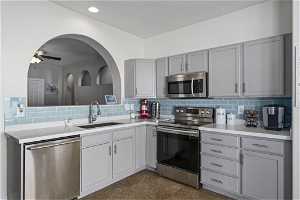 Kitchen featuring ceiling fan, dark tile floors, sink, tasteful backsplash, and stainless steel appliances