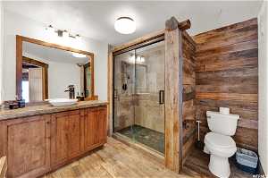 Bathroom featuring toilet, wood-type flooring, vanity, and a shower with shower door