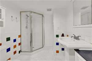 Bathroom with tile walls, toilet, tile floors, and a shower with shower door