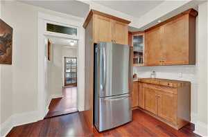 Kitchen with tasteful backsplash, dark hardwood / wood-style flooring, and stainless steel refrigerator
